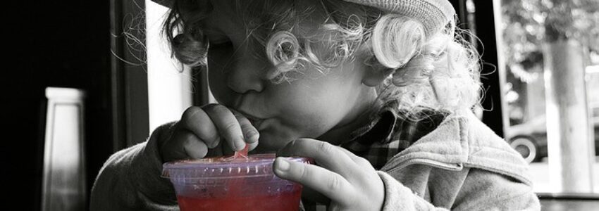 A small girl drinking kombucha.