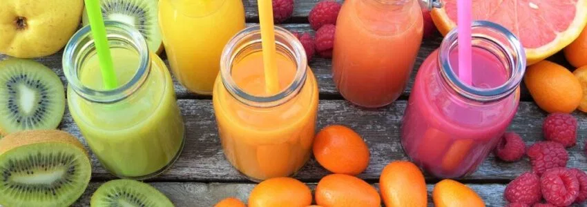 Smoothie in glass jars surrounded by fruits and vegetables