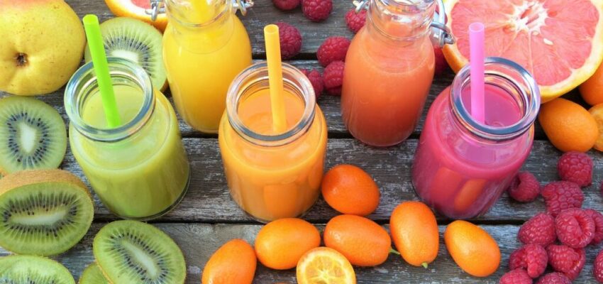 Smoothie in glass jars surrounded by fruits and vegetables