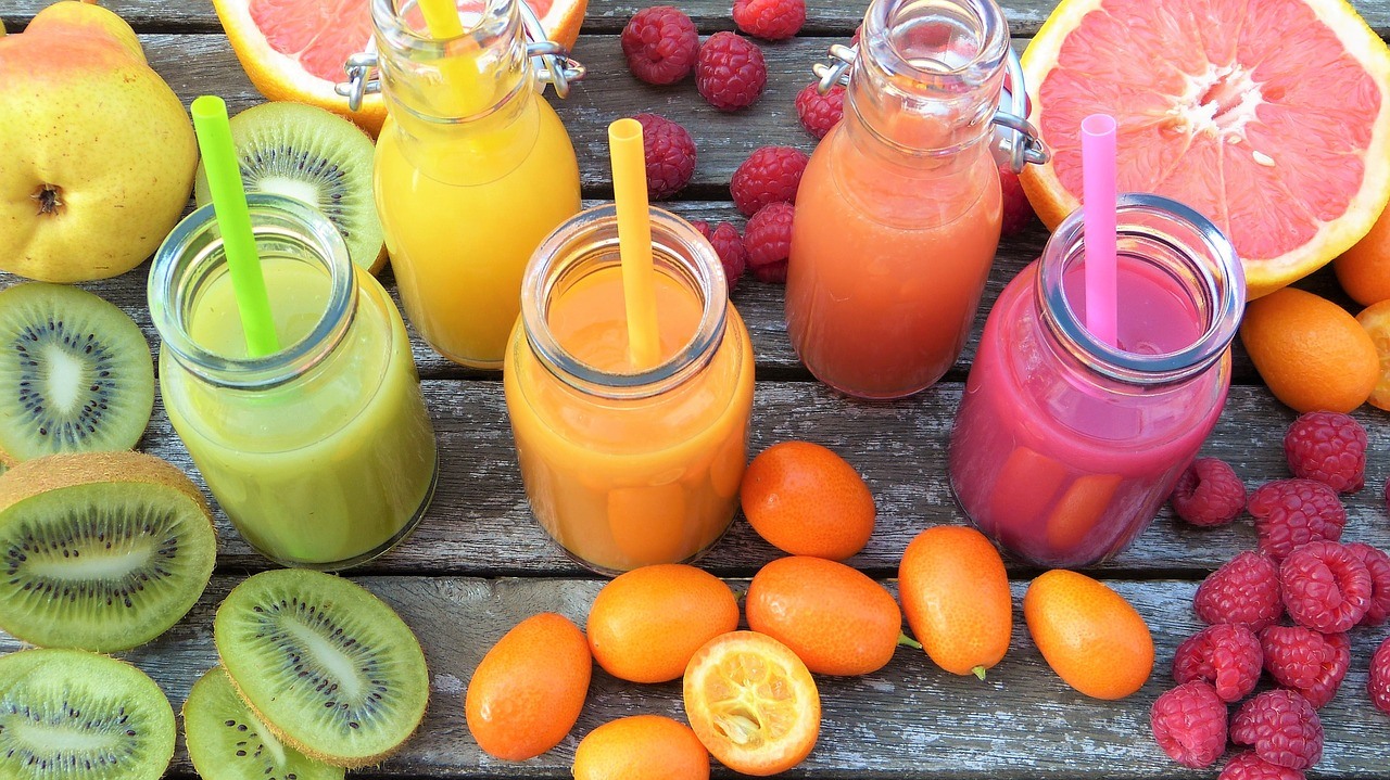 Smoothie in glass jars surrounded by fruits and vegetables