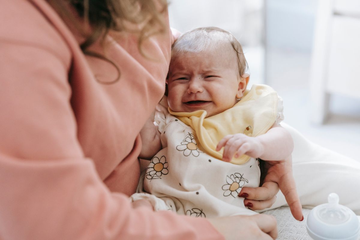 a crying baby carried by a woman trying to prevent constipation