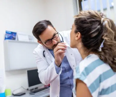 The woman consults the doctor because of strep throat.