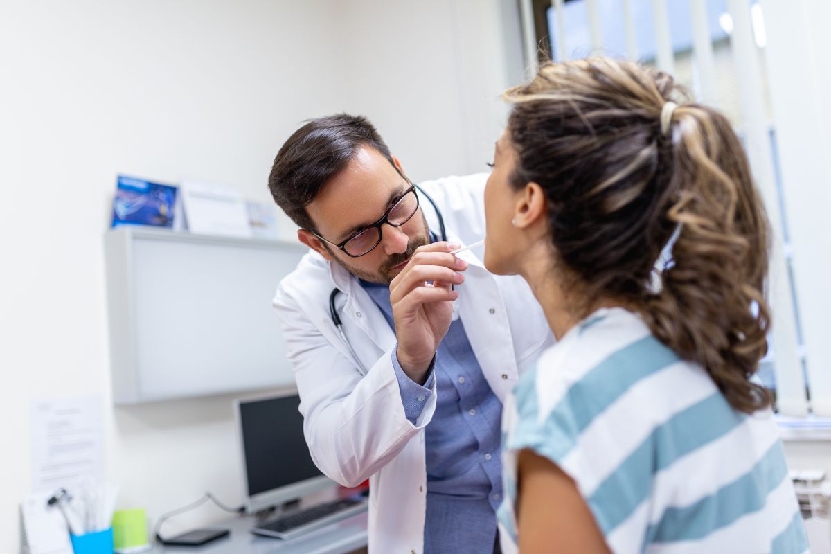 The woman consults the doctor because of strep throat.