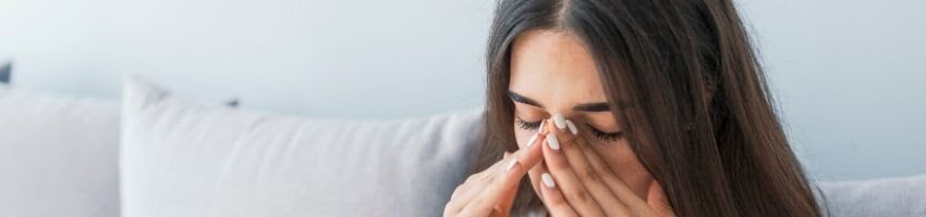 A woman holding her nose and trying to heal her sinus and headache