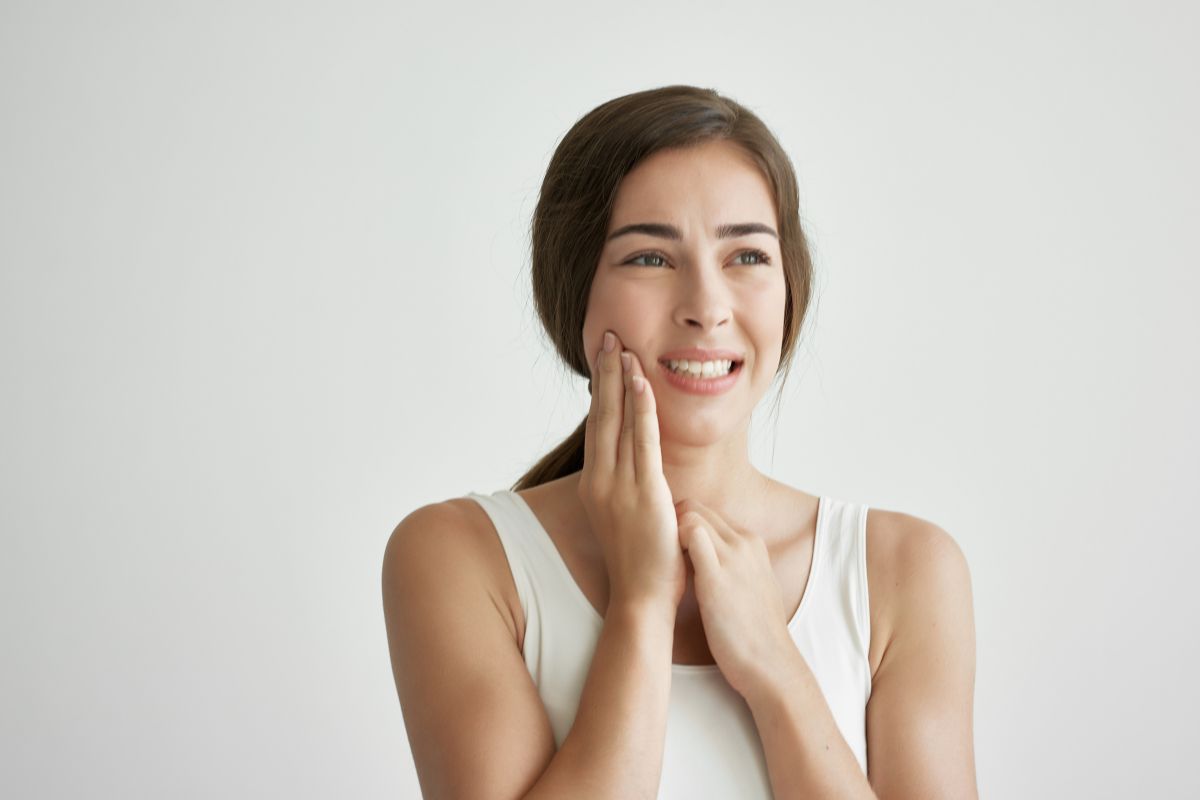 a woman in white sando shirt having a jaw pain