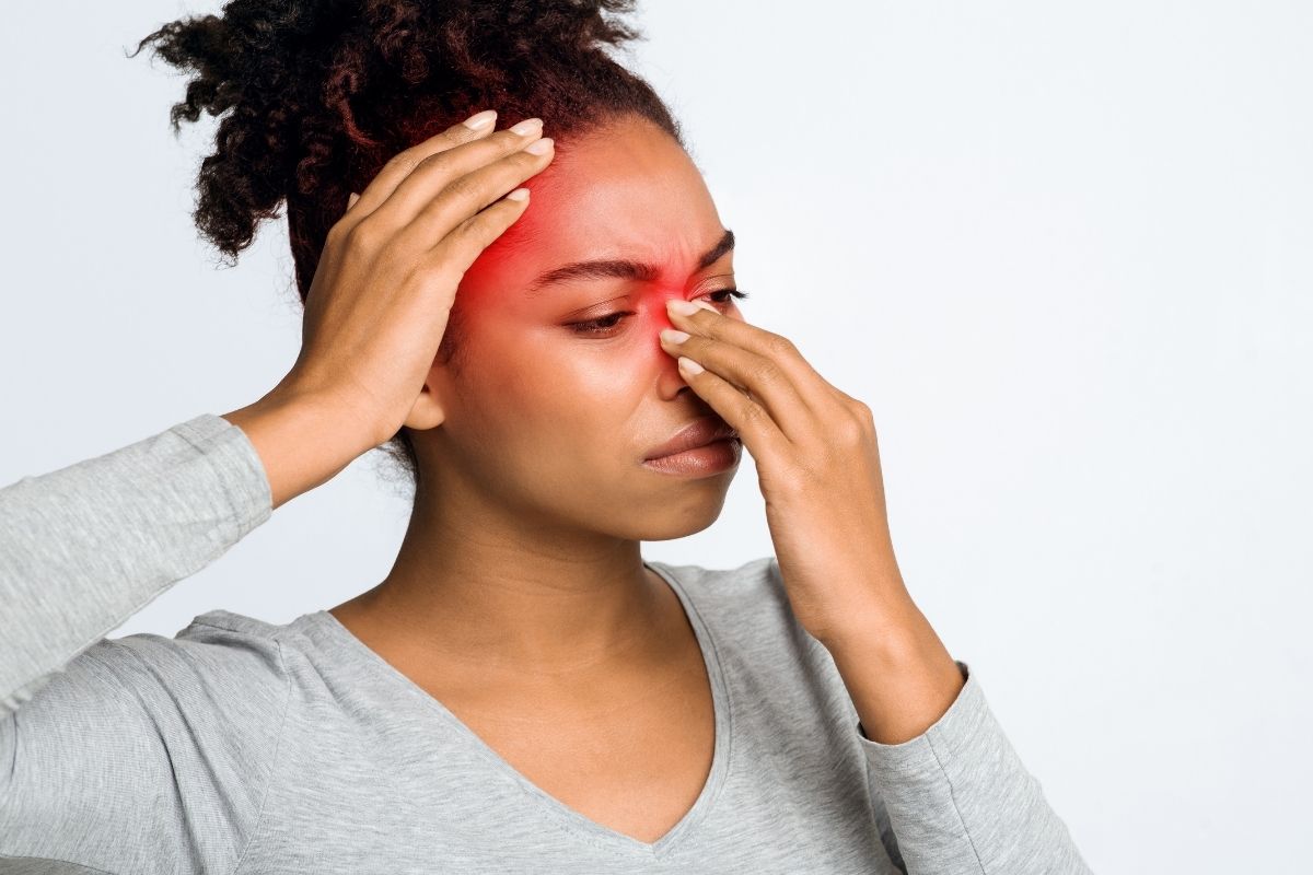 A woman holding her nose which has a sinus infection.