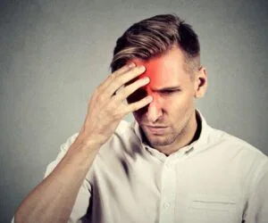 Man holding his head due to severe headache caused by sphenoid sinus infection.