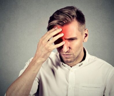 Man holding his head due to severe headache caused by sphenoid sinus infection.