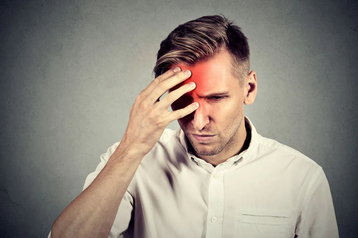 Man holding his head due to severe headache caused by sphenoid sinus infection.