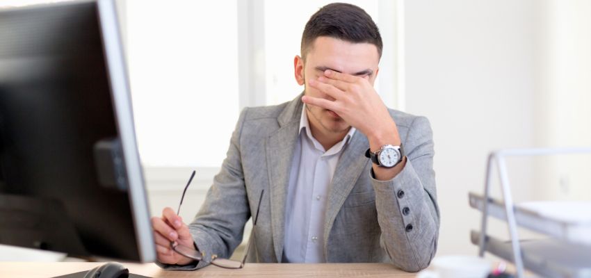 Man in an office experiencing pain and pressure behind the nose from sphenoid sinus infection.