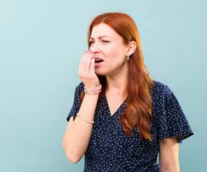The woman smells if her breath still stinks.