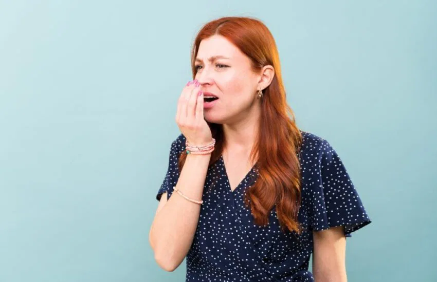 The woman smells if her breath still stinks.