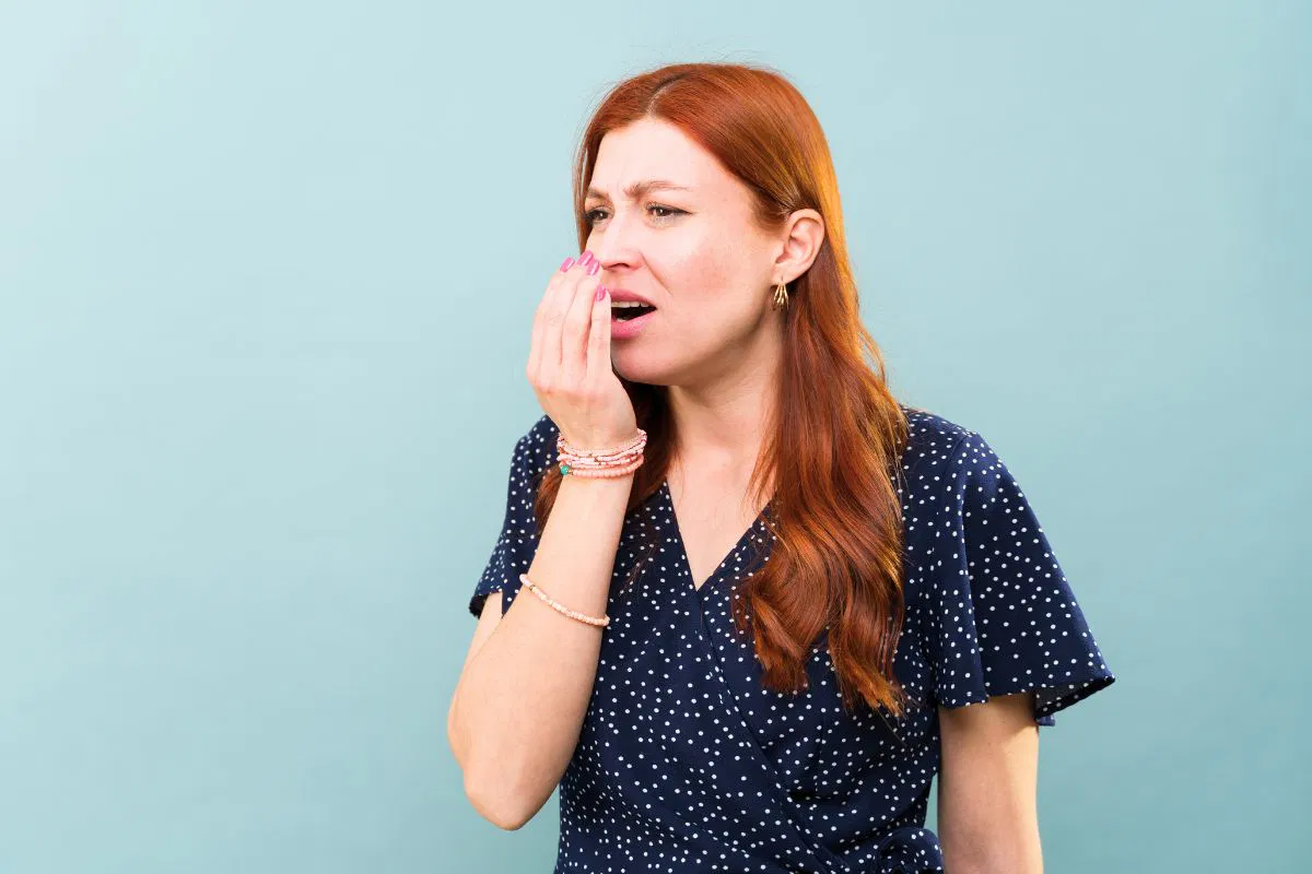 The woman smells if her breath still stinks.