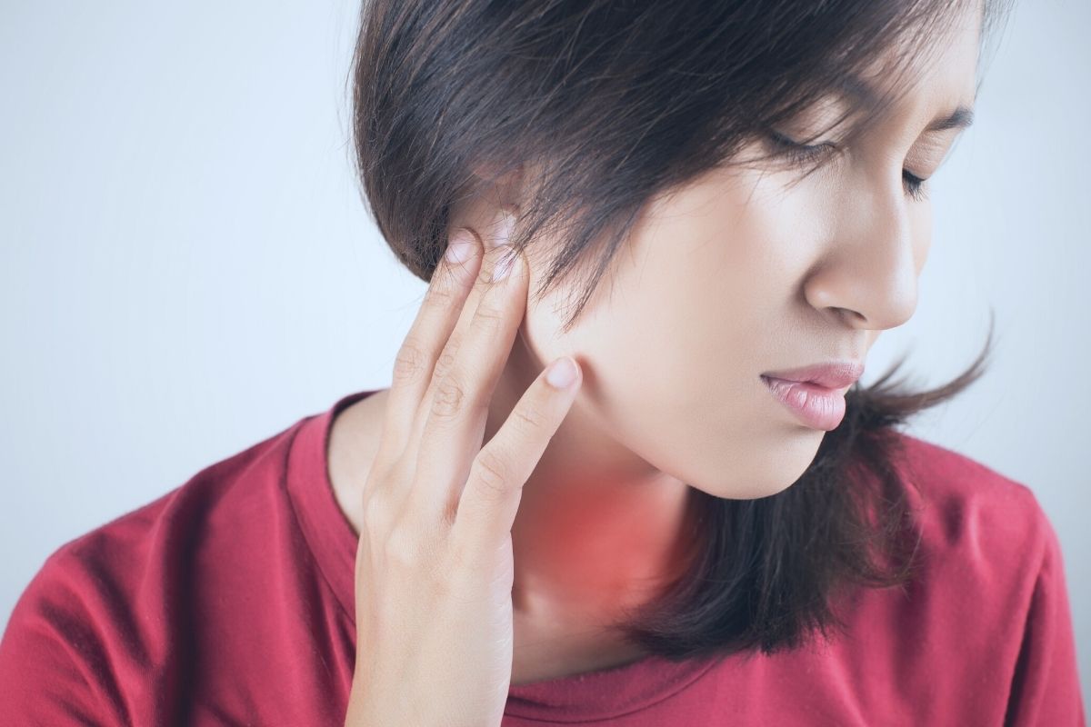 A woman suffering from sore throat and ear pain.