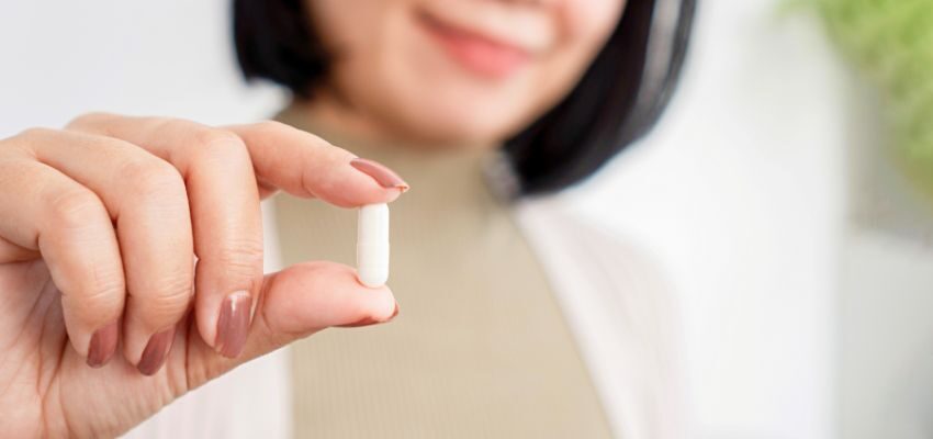 The woman is holding a probiotic supplement.