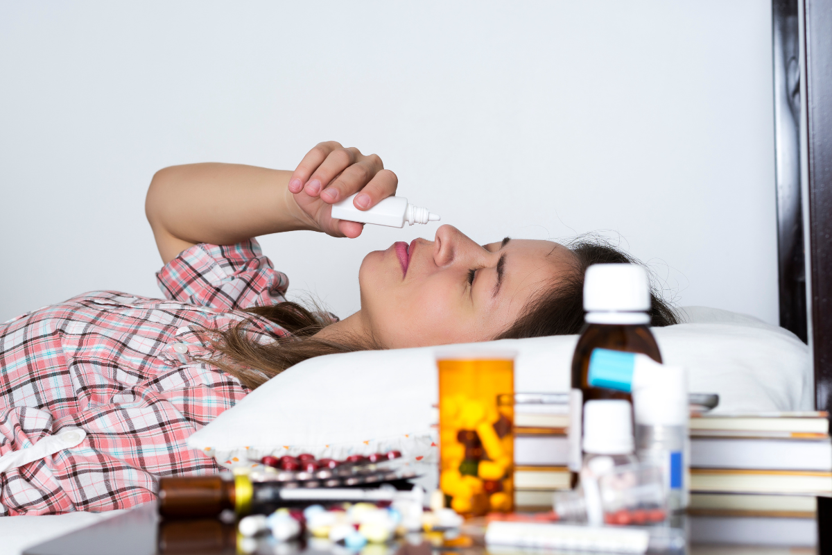 A woman lying in bed while inhaling a decongestant.