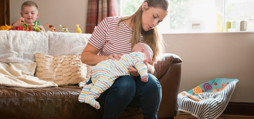 A baby lying facedown on her mother's lap.