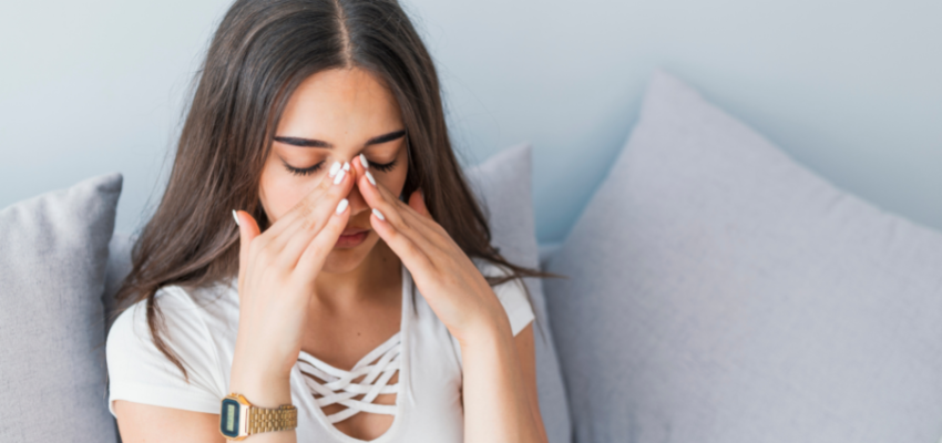 A woman is doing a frontal sinus massage herself.