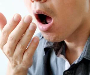 The man checks the smell of his breath.