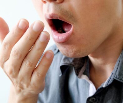The man checks the smell of his breath.