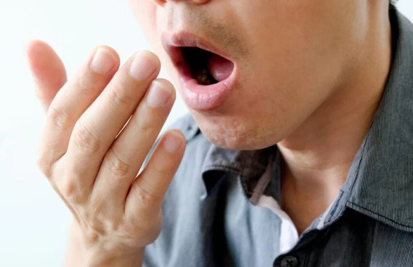 The man checks the smell of his breath.