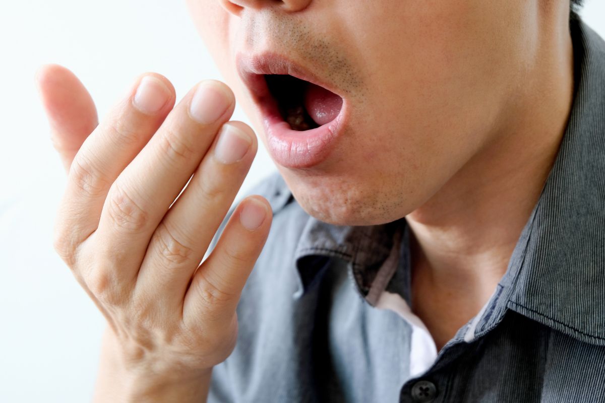 The man checks the smell of his breath.