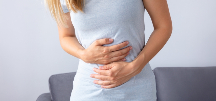 Woman holding her stomach in discomfort while learning how to stop protein farts