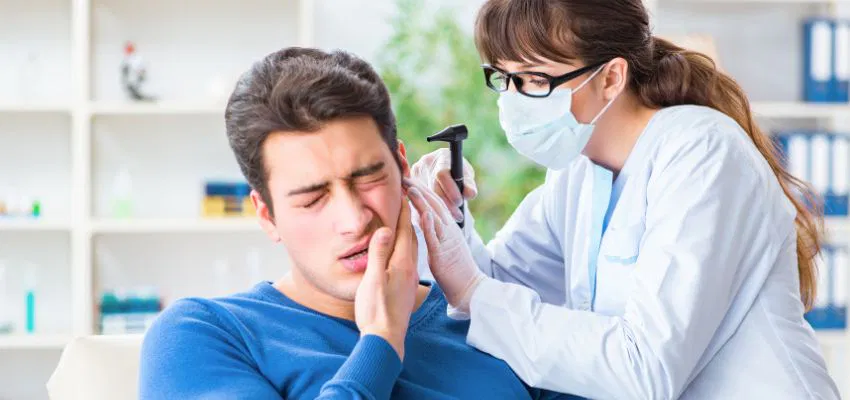 how-to-drain-ear-sinus-fluid2 Doctor examining a patient’s ear to check sinus fluid buildup and discuss how to drain ear sinus fluid.