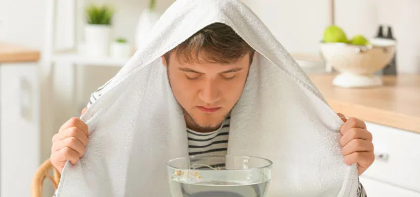 how-to-drain-ear-sinus-fluid3 Man using steam inhalation at home as a natural method for how to drain ear sinus fluid.