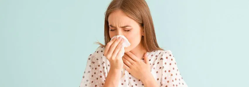 Frustrated woman holding her nose, wondering why does my nose whistle when I exhale.