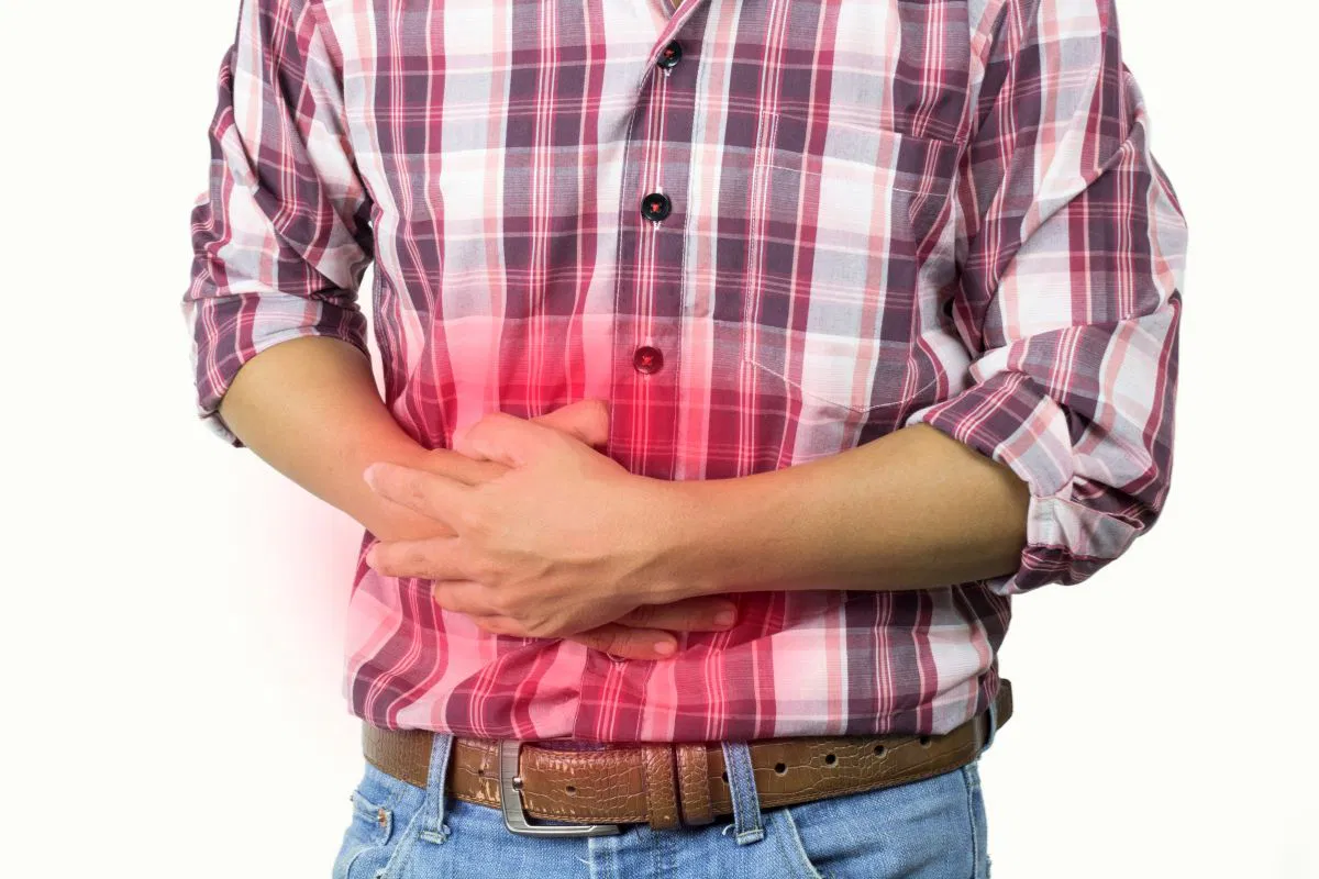 Man holding his stomach with red pain highlight, showing discomfort from constipation after antibiotics.