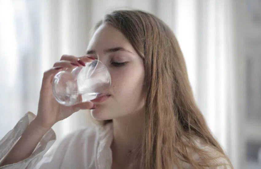 The woman is drinking water to prevent dehydration. 