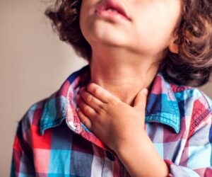 A toddler holding his neck due to the discomfort of sore throat
