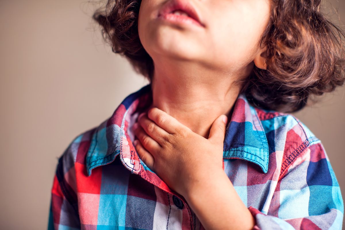 A toddler holding his neck due to the discomfort of sore throat