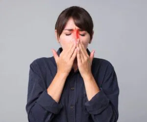 The woman is experiencing sinus pain.