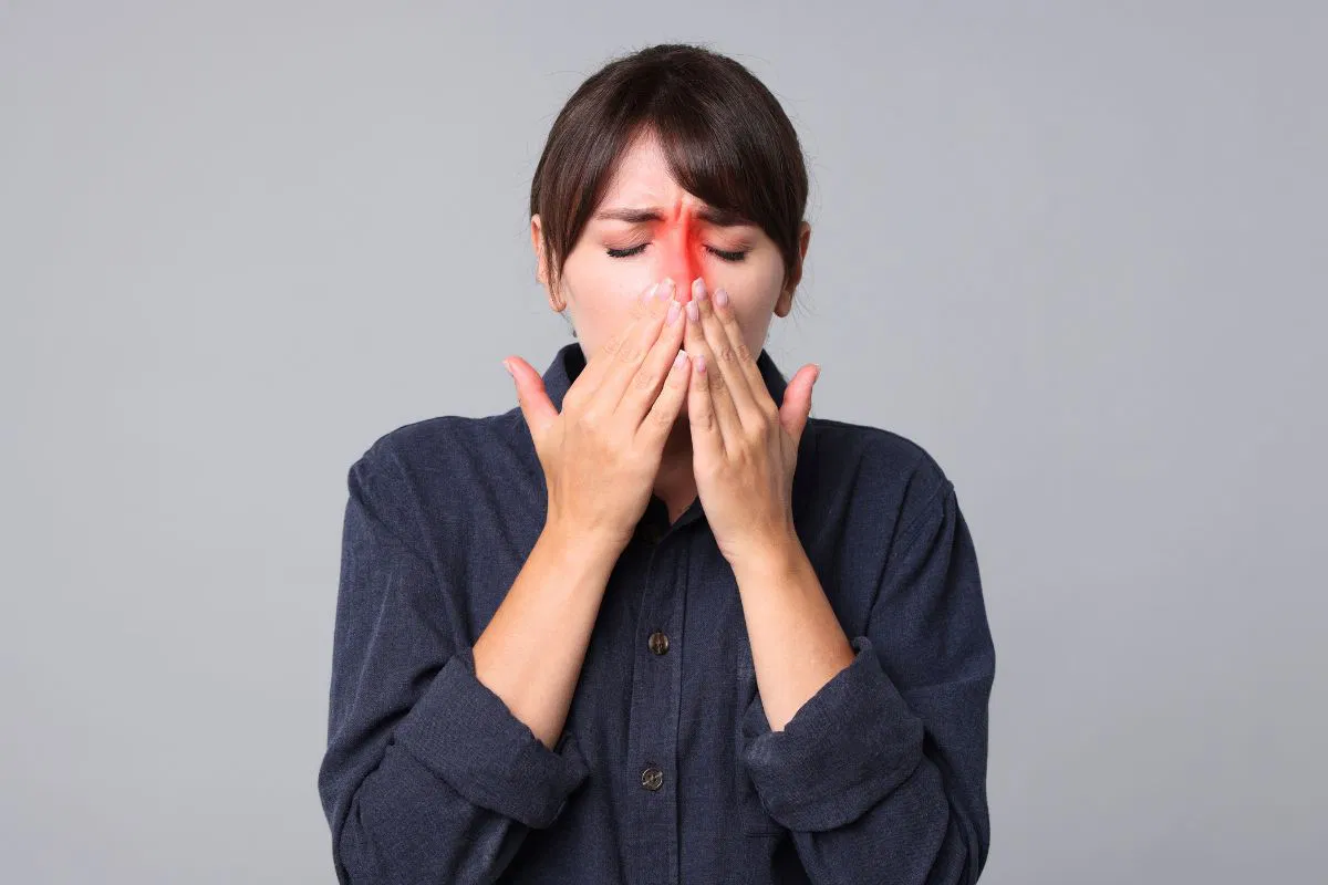 The woman is experiencing sinus pain.