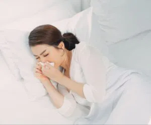 A woman sneezing with watery eyes, capturing the moment their nose-feels like inhaled water.