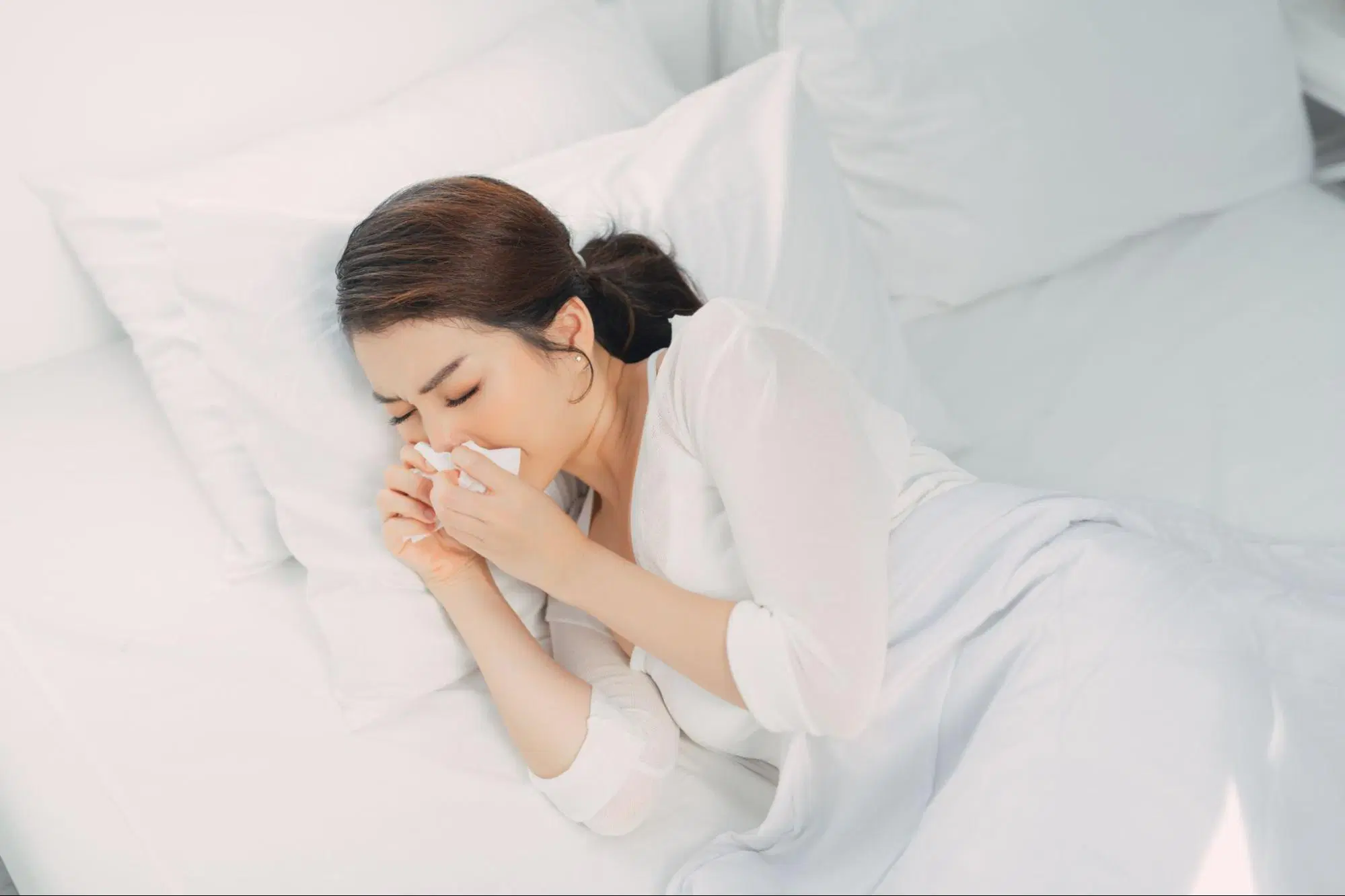 A woman sneezing with watery eyes, capturing the moment their nose-feels like inhaled water.