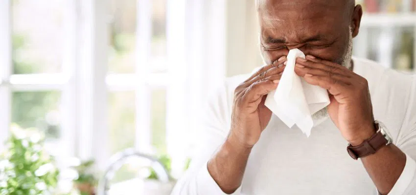 A man blowing his nose to depict that boosting immunity is one of the benefits of spicy food