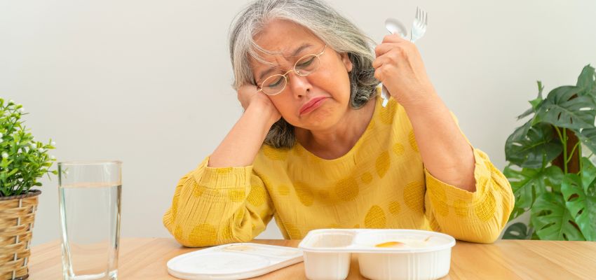 Elderly woman looking unhappy at mealtime as everything tastes salty