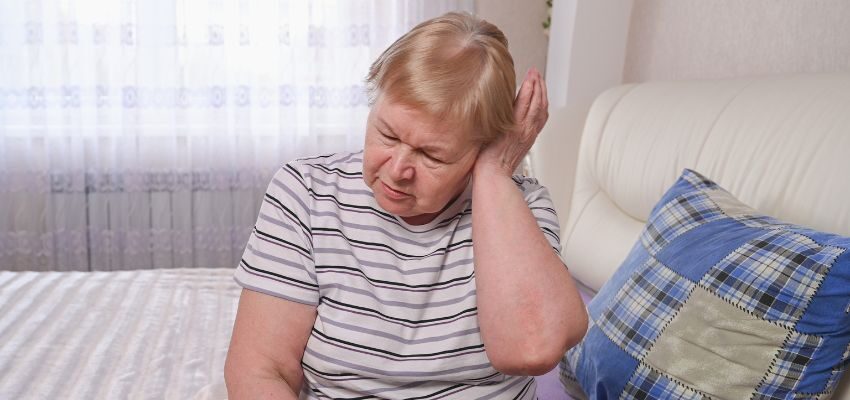 An older woman is suffering because of a ruptured eardrum.