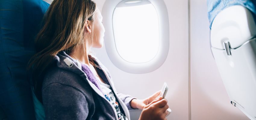 The woman is comfortable sitting on the plane.