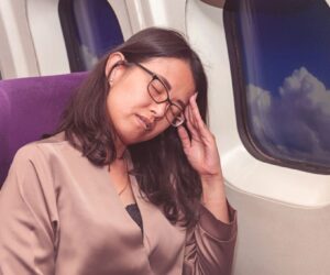 The woman is not comfortable sitting on the plane.