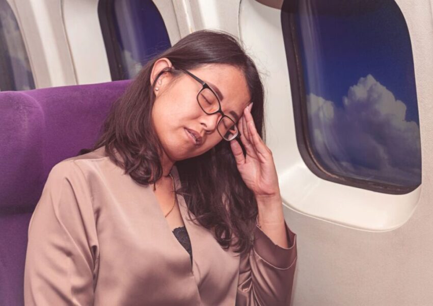 The woman is not comfortable sitting on the plane.