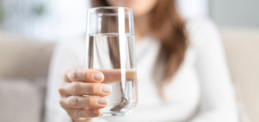 The woman drinks more water to ease strep throat.