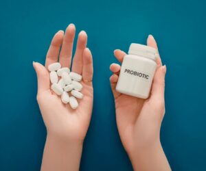 A person is holding a bottle of a probiotic supplement.