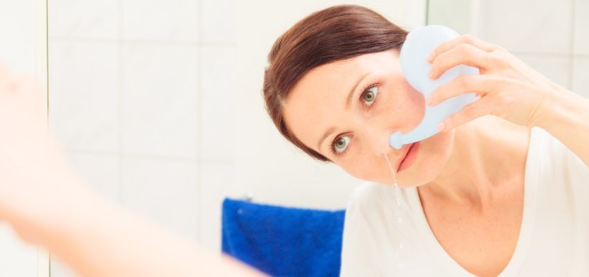 The woman does saline nasal rinse on her own.