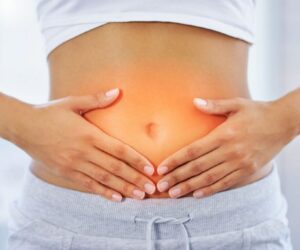 Person holding abdomen with highlighted discomfort area, illustrating benefits of probiotic fruits for gut health.