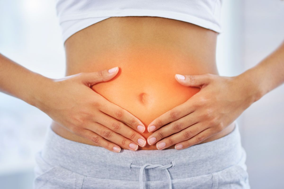 Person holding abdomen with highlighted discomfort area, illustrating benefits of probiotic fruits for gut health.