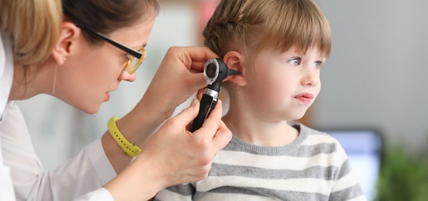 The doctor checks the girl to see if she has clogged ears.